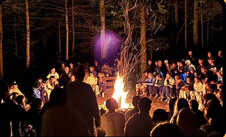 Youth gathered around an evening bonfire